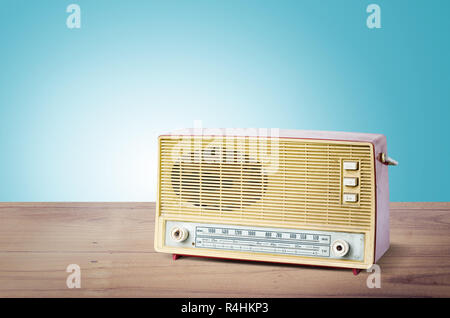 Vieille radio poussiéreux de 1970 sur table en bois avec fond bleu. Banque D'Images