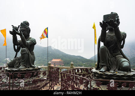 Statues bouddhiques en faisant des offrandes à l'Tian Tan Buddha (Big Buddha) avec monastère Po Lin en arrière-plan, Lantau Island, Hong Kong Banque D'Images