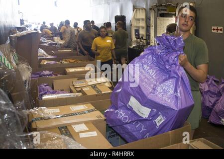 Golfe d'ADEN - U.S. Marine Cpl. David Berckman, un moteur avec l'opérateur de transport du bataillon logistique de combat 13, 13e Marine Expeditionary Unit (MEU), porte un sac de courrier au cours d'un ravitaillement en mer à bord de la classe Whidbey Island landing ship dock USS Rushmore (LSD 47), le 21 septembre 2018. Le groupe amphibie d'Essex et 13e MEU sont déployés dans le domaine de la 5e flotte américaine des opérations à l'appui des opérations navales pour assurer la stabilité et la sécurité maritime dans la région Centrale, reliant la Méditerranée et le Pacifique à travers l'ouest de l'Océan indien et trois points d'étranglement stratégiques Banque D'Images