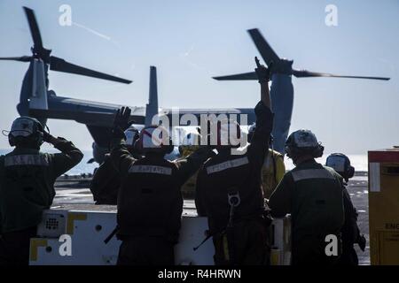 Les Marines américains avec l'escadron 166 à rotors basculants moyen maritime renforcée, 13e Marine Expeditionary Unit (MEU), vague à d'autres marines à bord d'un MV-22B Balbuzard comme il décolle à bord de la classe Wasp-navire d'assaut amphibie USS Essex (DG 2), le 3 octobre 2018. L'Essex est le navire amiral de la Essex Groupe amphibie et, avec l'entrepris 13e MEU, est déployé à la 5e Flotte des États-Unis zone d'opérations à l'appui des opérations navales pour assurer la stabilité et la sécurité maritime dans la région Centrale, reliant la Méditerranée et le Pacifique à travers l'ouest de l'Océan indien et trois starter stratégique po Banque D'Images