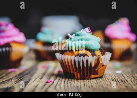 Cupcake chocolat avec crème de couleur rose et vert sur la table en bois Banque D'Images