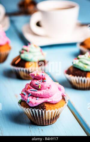 Cupcake chocolat avec crème de couleur rose et vert sur la table bleu Banque D'Images