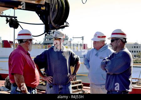 De gauche à droite, Scott Titus, U.S. Army Corps of Engineers du District de Norfolk, ingénieur du port de Colonna Colonna's Shipyard Inc., Glen Boykin, derrick voile Elizabeth les machines de mécanicien, et Richard Bruton, DB Elizabeth capitaine, se tenir sur le pont de la DB Elizabeth car elle se situe à la cale sèche du chantier naval de Colonna Inc., Norfolk, en Virginie, le 29 octobre 2018. Le bateau, une partie de la flotte du USACE, est souvent utilisé pour l'enlèvement des débris dans et autour de ses eaux territoriales de Norfolk, en Virginie. Banque D'Images