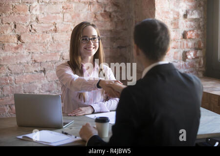 Friendly attractive young woman handshaking businessman at meeti Banque D'Images