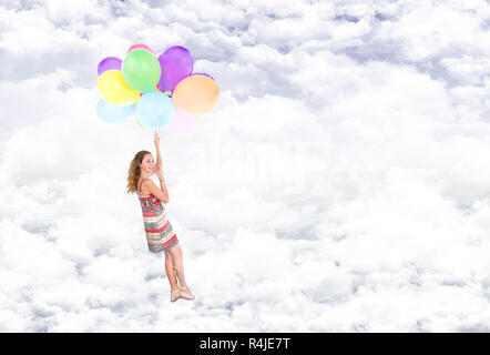 Girl hanging sur ballons voler dans les nuages Banque D'Images