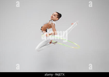 La teen femme petite fille faisant des exercices de gymnastique avec hoop isolé sur un fond gris studio. L'étirer, gymnastique, fitness, mode de vie, de formation, de sport concept Banque D'Images