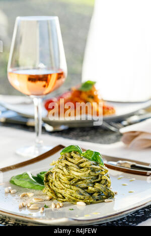 Pesto pâtes léger déjeuner avec verre de vin rose Banque D'Images