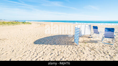 Chaises bleu et blanc et à l'abri du vent plage déserte Banque D'Images