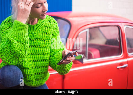 Concept de couleur mode image avec blonde woman standing près d'une vieille voiture vintage rouge bleu avec mur d'acier en backgorund. Et les couleurs urbaines wit Banque D'Images