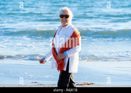 Belle femme plus âgée à la retraite marche sur automne hiver plage sur le coucher du soleil en compagnie de ses liberté se sentir heureux et chanceux en vie active et en af Banque D'Images