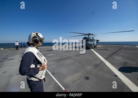 Océan Atlantique (oct. 28, 2018) - Ensign Steffi Yo observe un Sea Hawk MH-60S'hélicoptère sur le pont d'envol du navire de débarquement amphibie dock USS Fort McHenry (LSD 43) dans le cadre du groupe aéronaval (CSG) 4 unité de formation composite (exercice COMPTUEX). COMPTUEX est le dernier exercice de pré-déploiement qui certifie l'ensemble groupe amphibie Kearsarge (ARG) et 22e Marine Expeditionary Unit (MEU) capacité à mener des opérations militaires en mer et à terre par la puissance du projet la planification conjointe et l'exécution des scénarios de formation réalistes et stimulants. CSG 4 mentors, trains et Banque D'Images