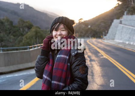 Jeune femme posant sur la route à l'aube avec un beau lever de soleil Banque D'Images