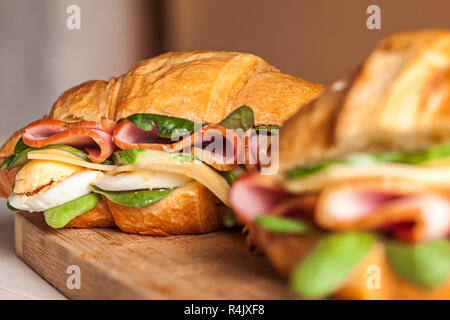 Les croissants sandwiches sur la planche à découper en bois Banque D'Images