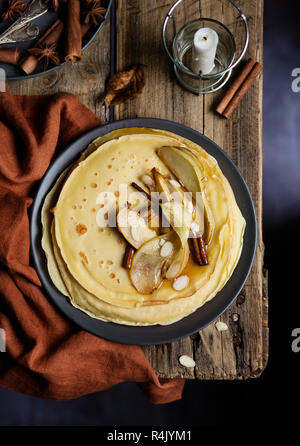 Crêpes sucrées avec poires caramélisées, la cannelle et les amandes sur table en bois. Vue d'en haut Banque D'Images