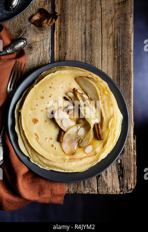 Crêpes sucrées avec poires caramélisées, la cannelle et les amandes sur table en bois. Vue d'en haut Banque D'Images