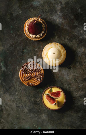 Variété de sweet tartelettes au chocolat, caramel, poires, figues plus vieux dark metal texture background. Mise à plat, de l'espace Banque D'Images