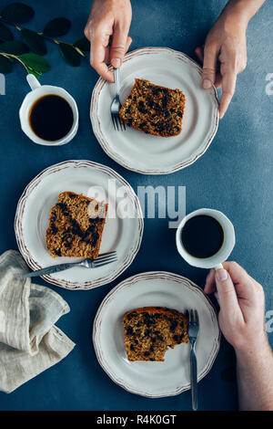 Deux personnes le petit-déjeuner avec pain aux bananes et aux grains de chocolat servi sur des assiettes blanches et de thé. Banque D'Images