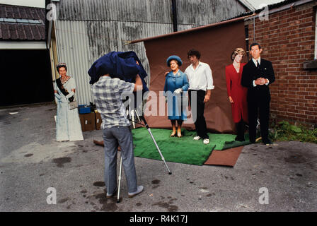 Les courses d'Ascot Angleterre UK 1986 numérisé en 2018 photographe entreprenants venir un studio photographique pour capturer les membres du public avec découpe de la famille royale britannique dans les rues d'Ascot le jour de la course. Banque D'Images