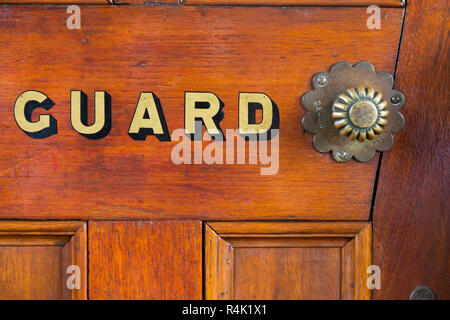 Le mot Guard peint en lettres d'or / lettres sur la porte de la garde van / van de frein sur un vieux train à vapeur vintage transport. England UK. (98) Banque D'Images