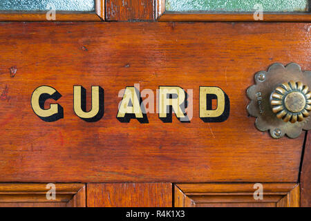 Le mot Guard peint en lettres d'or / lettres sur la porte de la garde van / van de frein sur un vieux train à vapeur vintage transport. England UK. (98) Banque D'Images