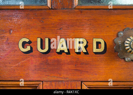 Le mot Guard peint en lettres d'or / lettres sur la porte de la garde van / van de frein sur un vieux train à vapeur vintage transport. England UK. (98) Banque D'Images