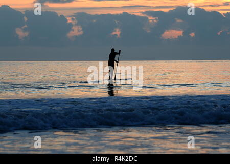 Stand Up Paddle boarder sur mer calme au coucher du soleil d'or Banque D'Images