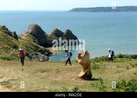 Les promeneurs sur le sentier des sculptures à la suite de la côte Gower UK à trois Cliffs bay. Oxwich point est la pointe à l'horizon. Banque D'Images