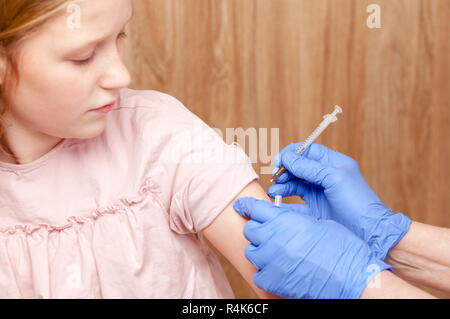 Close-up shot de pédiatre en donnant une injection intramusculaire d'un vaccin à un preteen girl's Arm - concept de vaccination des enfants Banque D'Images