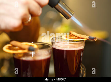 Barman burns les bâtons de cannelle et d'agrumes tranche pour vin chaud cocktail au froide journée d'hiver Banque D'Images