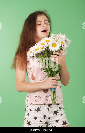 Portrait de jeune femme brune rif, avoir une réaction allergique aux fleurs - camomille, selective focus. Isolé sur fond vert Banque D'Images