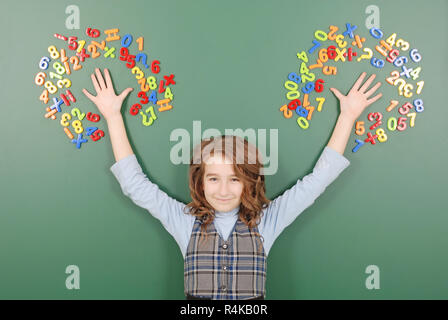 Jeune fille se tient devant un conseil de l'école verte avec des aimants de chiffres sur fond vert Banque D'Images