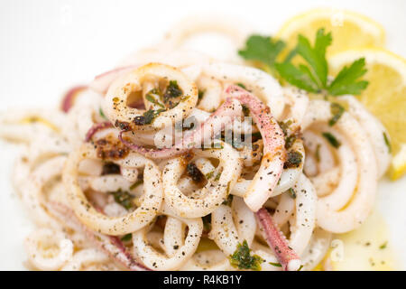 Frais d'un calmar Loligo vulgaris, pris sur la tige et à la ligne, qui a été tranchés en rondelles et sautés au beurre avec le persil et le jus de citron et dispersés Banque D'Images