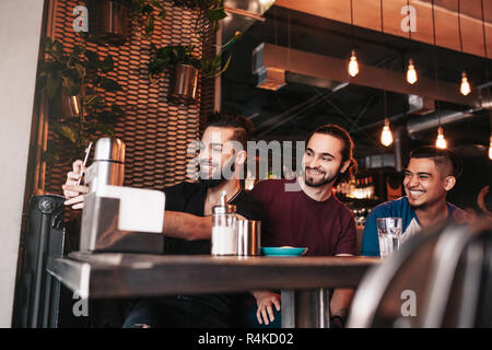 Groupe d'amis arabes prenant en selfies bar-salon. Mixed Race jeunes hommes ayant in loft cafe Banque D'Images