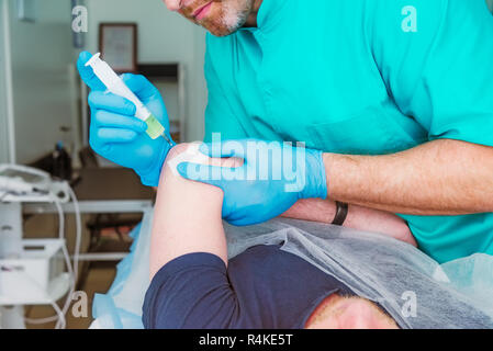 Close up neurologue médecin fait une thérapie par injection (blocus) dans le muscle de l'articulation du coude de patient de sexe masculin. Le traitement de la douleur Alternative concept. Selecti Banque D'Images