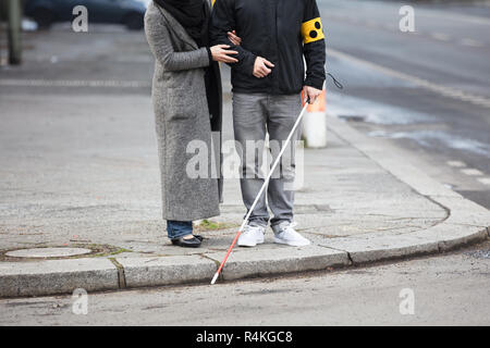 Femme avec un aveugle dans la rue Banque D'Images