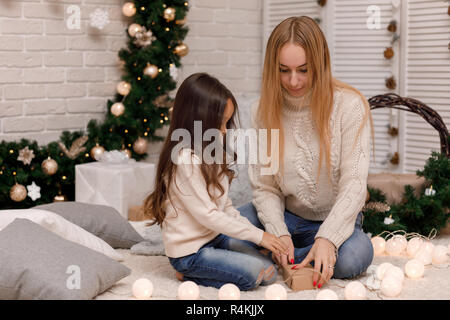 La mère et l'enfant fille cadeaux de Noël à la maison. Banque D'Images