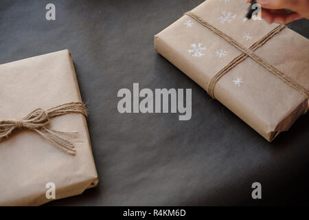 Dessin sur papier femme Flocons de paquet cadeau de Noël fort sur fond noir. La peinture sur les mains des femmes présente pour les vacances d'hiver. Noël, ne Banque D'Images