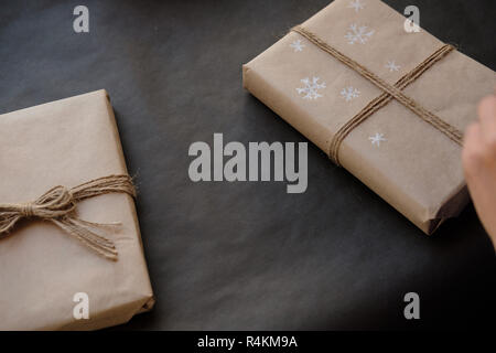 Dessin sur papier femme Flocons de paquet cadeau de Noël fort sur fond noir. La peinture sur les mains des femmes présente pour les vacances d'hiver. Noël, ne Banque D'Images