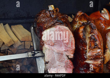 Close up plusieurs gros morceaux de jambon de porc en rotation de la viande d'être uniformément grillés sur feu de bois ouvert brochette, high angle view Banque D'Images