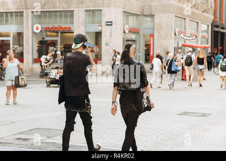 Allemagne, Leipzig, le 6 septembre 2018 : jeune couple de punks ou amis marcher dans les rues de Leipzig. Il écoute de la musique sur le téléphone. Sous-culture de la jeunesse. Banque D'Images