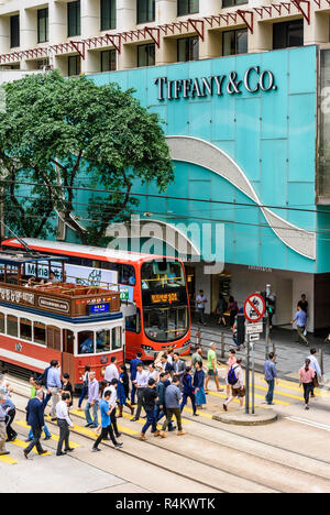 Les personnes qui traversent la rue en face de la boutiques de luxe le long Des Voeux Road, Central, Hong Kong Banque D'Images