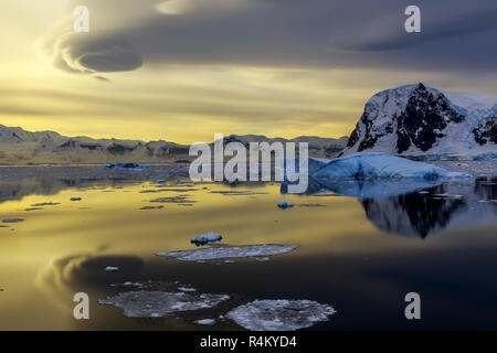 Iceberg bleu, les montagnes et le coucher du soleil se reflétant dans le détroit de Lemaire à l'océan, l'Antarctique Banque D'Images