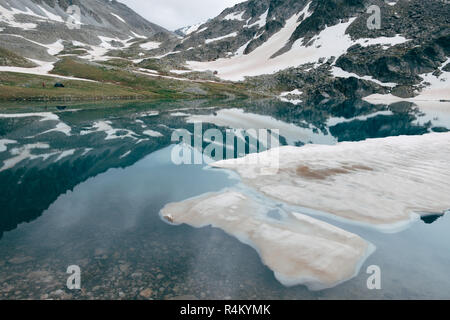 Banquise dérive du mountain cold lake. Sommets enneigés reflétée dans un miroir de l'eau Banque D'Images