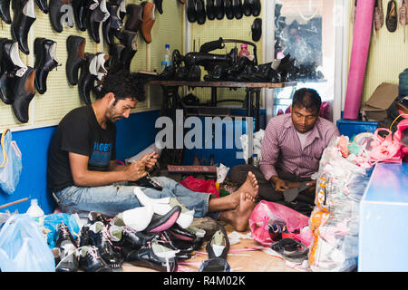 Katmandou, Népal - Avril 2015 : deux cordonniers travaillant sur des chaussures dans leur atelier. Banque D'Images