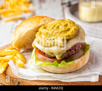 Hamburger délicieux servi avec une garniture de guacamole et des frites. Banque D'Images