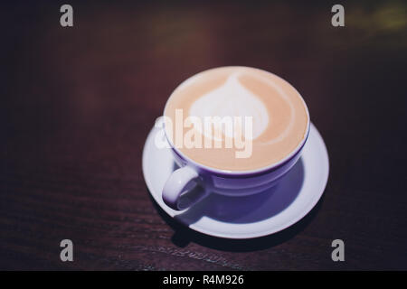 Tasse de café café latte avec coeur latte art sur le dessus.