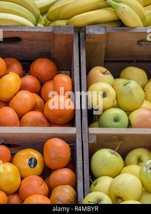 Les pommes, les oranges et les bananes en vente sur un étal de légumes dans un marché vendant des fruits et légumes frais. Banque D'Images