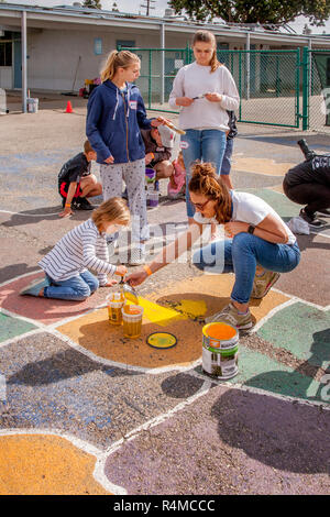 Les étudiants, professeurs et parents bénévoles travaillent à repeindre et de restauration d'un site de l'US dans une cour d'école à Costa Mesa, CA. Banque D'Images