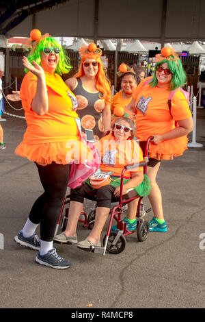 Un fauteuil-bondissent senior woman est rejoint par ses filles adultes dans des costumes amusants car ils tous se préparer à exécuter dans un comté communauté course à pied juste à Costa Mesa, CA. Banque D'Images