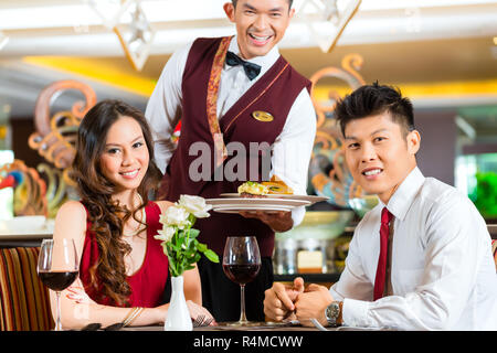 Serveur chinois servant le dîner dans l'élégant restaurant ou hotel Banque D'Images